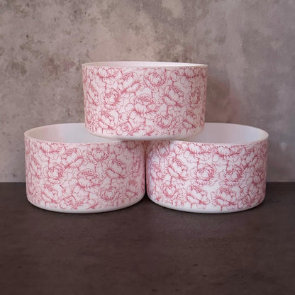 May include: Three white ceramic bowls with a pink floral pattern stacked on top of each other